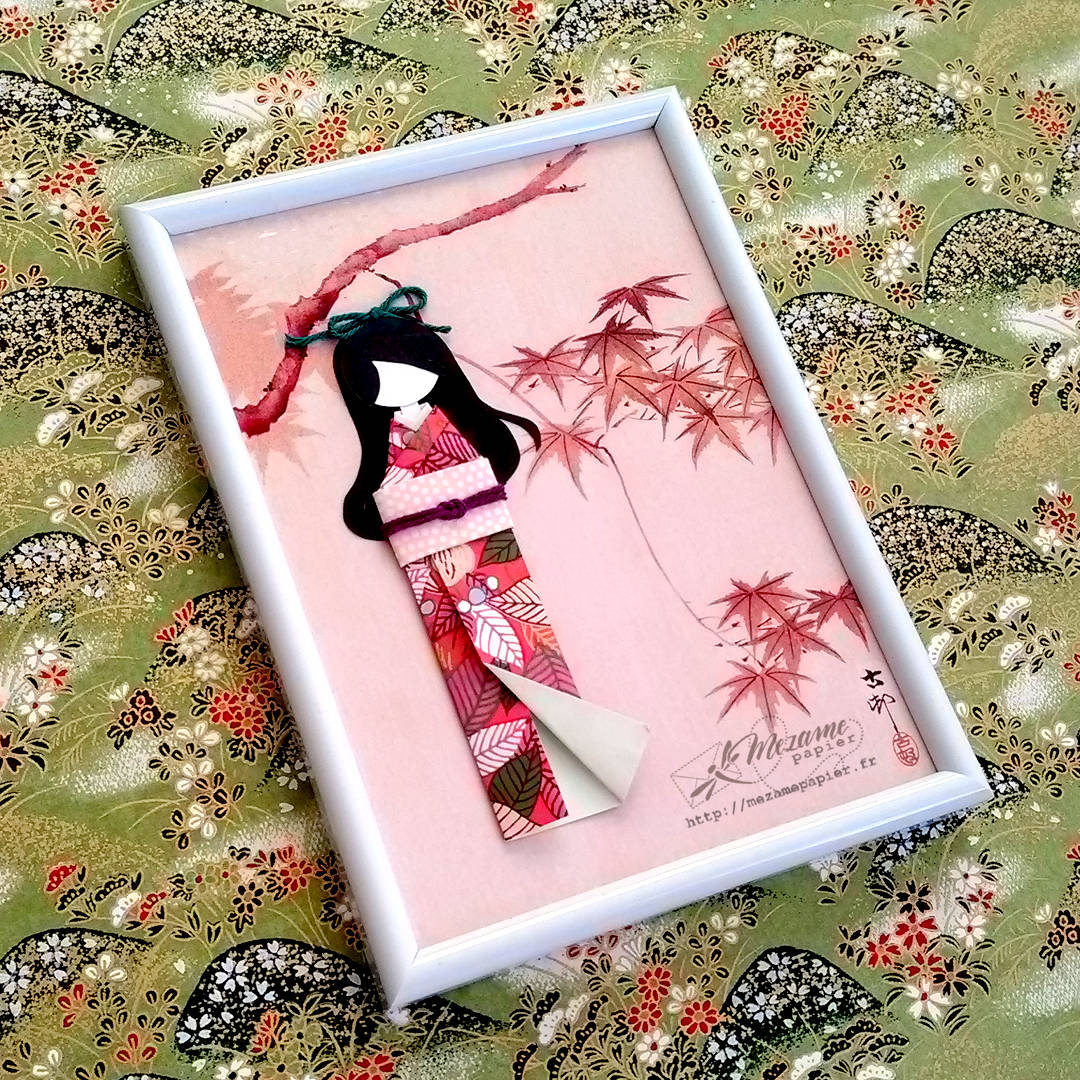 Poupée en papier portant un kimono automnal dans un cadre décoré de feuilles d'érable rouge